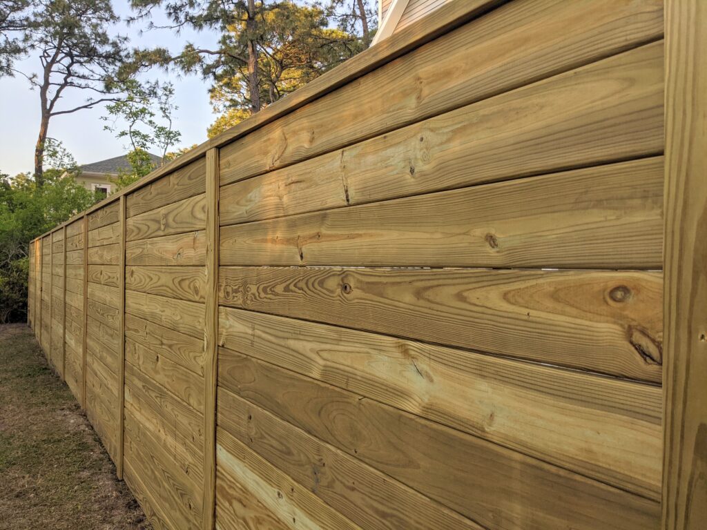 Wood fence installed by Two Brothers Fencing along a wooded lot line